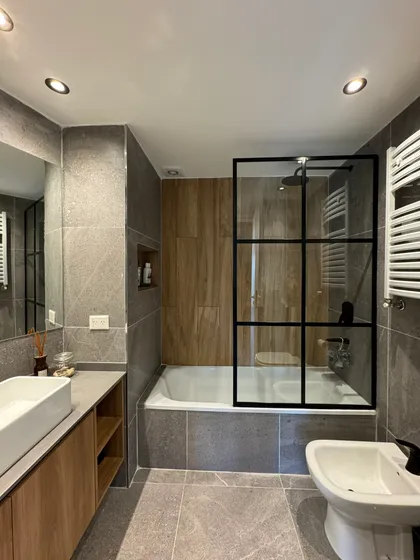 Baño moderno industrial con bañera exenta, ducha de vidrio y detalles en madera — proyecto Salguero II, por MDBK Arquitectura, en Palermo