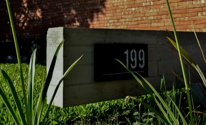 fachada moderna de hormigón con número 199 — proyecto CASA HC, por Daniel Daniele - Oficina de Arquitectura, en Canning