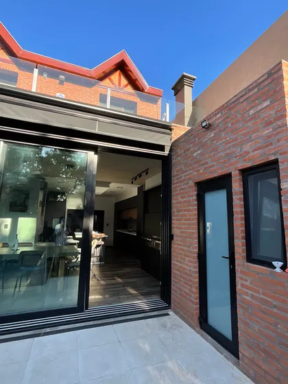 Fachada moderna de ladrillo con grandes ventanales y patio — proyecto JUAN AGUSTIN GARCIA, por Novoa Clerici arquitectos, en Buenos Aires