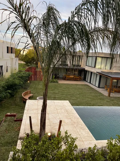 Pileta moderna con banco curvo y palmera — proyecto COSTA ESMERALDA, por Baires Green, en Pinamar
