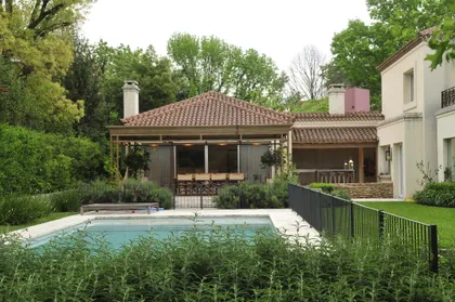 Amplia vista de piscina residencial con vegetación y quincho — proyecto Casa T6, por Estudio Junor, en Pilar
