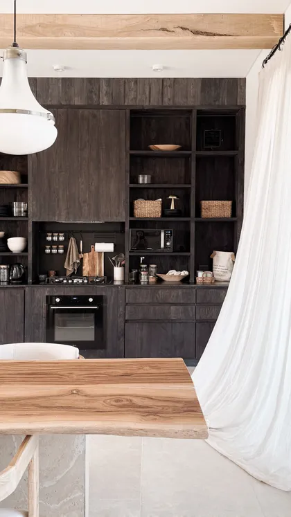 Cocina rústica con mesa de madera natural y vigas a la vista — proyecto El Refugio, por Grupo Pauta Arquitectura, en Pinamar