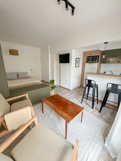 Living comedor con cocina integrada y sillones de madera — proyecto Reforma para alquiler temporal, por Gisela Salis, en Mar del Plata