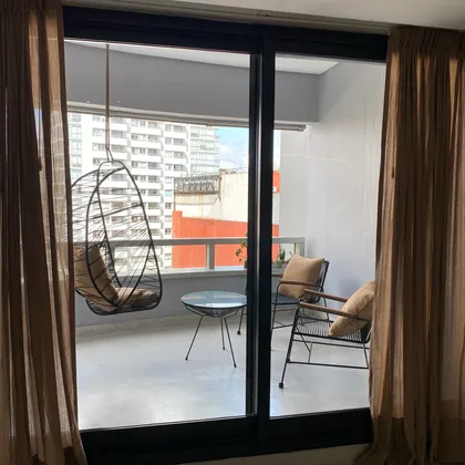 Balcón con silla colgante y vista urbana — proyecto Juncal II, por MDBK Arquitectura, en Palermo