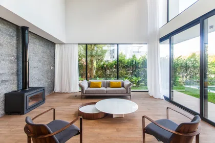 Living moderno con chimenea negra y grandes ventanales — proyecto CASA WINDBELLS, por ABAD GADANO, en Tigre