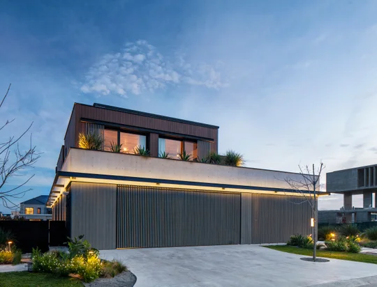 Fachada contemporánea nocturna con garaje y ventanales iluminados — proyecto Obra Wharehouse, por lifecycle, en B1648 Tigre