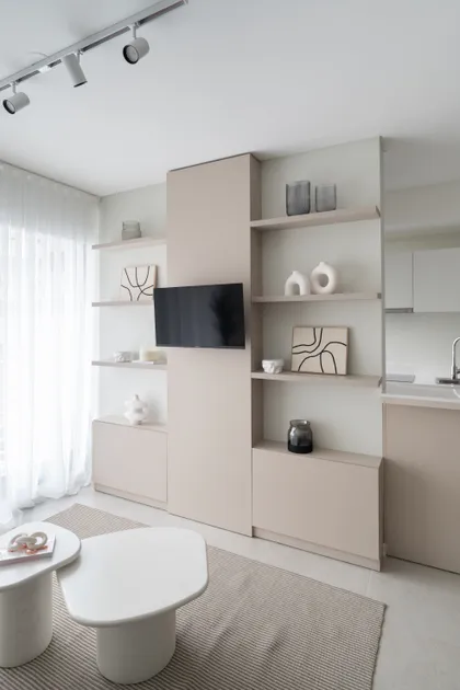 Living minimalista con estantería modular beige y mesas de café orgánicas — proyecto EVOQUE, por MB Díseño Interior , en Buenos Aires