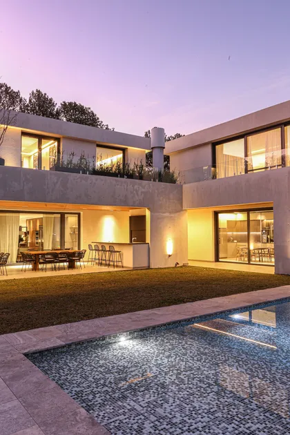 Amplia vista de casa moderna con piscina al atardecer — proyecto SD 45, por Estudio Arq Daniel Tarrio