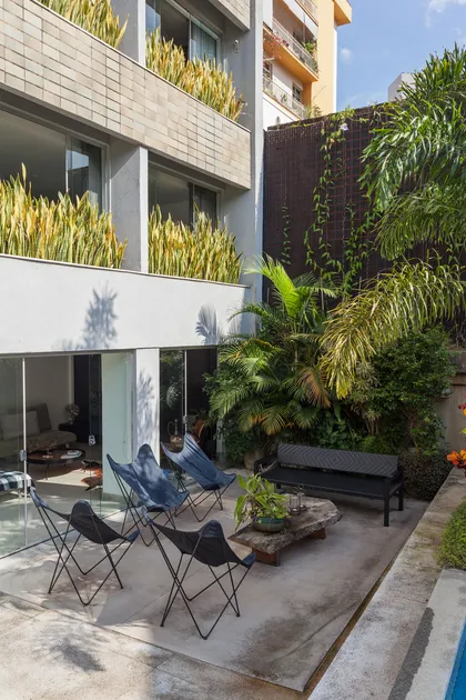 Patio moderno con jardineras verticales, sillas negras y plantas — proyecto APARTAMENTO FL, por Frederico Bicalho Arquitetura