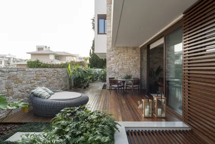 Terraza moderna con deck de madera, pérgola y muros de piedra — proyecto Casa C.A.P., por Ruschel Arquitetura e Urbanism