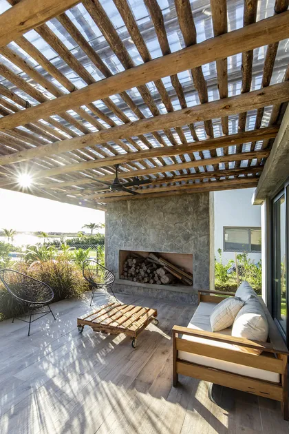 Terraza con pergola de madera, deck, hogar y mobiliario moderno — proyecto Casa ES, por Facundo Arana Arquitecto