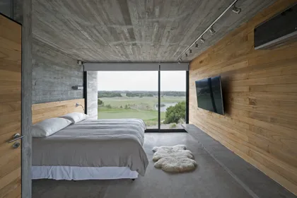 Dormitorio moderno con cama frente a ventanal panorámico de campo — proyecto Casa Golf, por Luciano Kruk