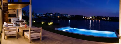 Patio moderno con piscina infinita y vista al lago de noche — proyecto Casa Nordelta, por linearecta.arquitectura, en Nordelta
