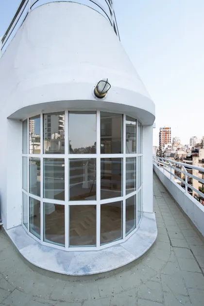Terraza curva con vista urbana y gran ventanal de estilo moderno — proyecto Montevideo, por Parq Estudio, en CABA