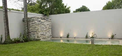 Patio moderno con piscina, pared de piedra y césped — proyecto Casa Estilo Francés, por Estudio Fernandez Long & asoc., en Martínez