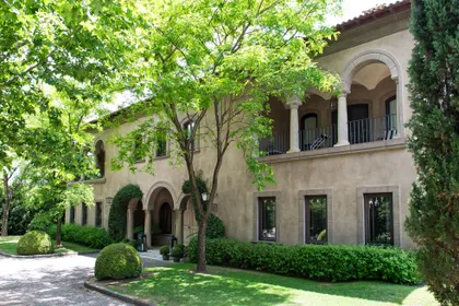 Fachada de casa mediterránea con arcadas, árboles y jardín verde — proyecto Casa Toscana , por Estudio Du 