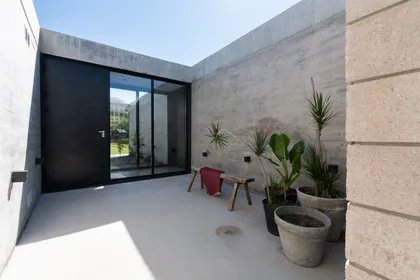 Terraza minimalista con macetas y ventanal negro hacia jardín — proyecto Casa SI, por Grupo Studio, en Villa Allende