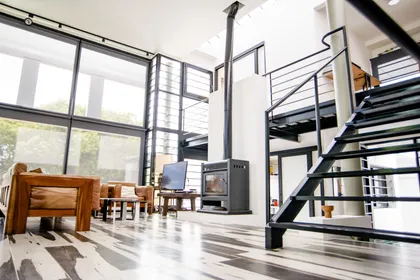 Living moderno industrial con doble altura y escalera flotante — proyecto CASA GONNET, por LEONE LORAY ARQUITECTOS, en Gonnet