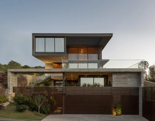 Casa contemporánea con fachada de hormigón, madera y amplios ventanales — proyecto Casa M.T., por Ruschel Arquitetura e Urbanism