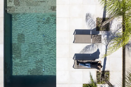Pileta rectangular con agua cristalina vista aérea, deck y palmeras — proyecto Casa 11, por Coda Arquitetos