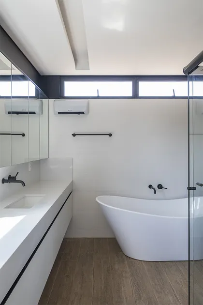 Bano minimalista con banera blanca, mesada blanca y piso de madera — proyecto Casa 636, por Coda Arquitetos
