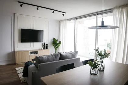 Sala de estar moderna con grandes ventanales y luz natural — proyecto Departamento Airbnb, por Jeitinho Estudió Creativo, en La Plata