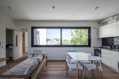 Living comedor cocina moderno con gran ventanal y muebles blancos — proyecto Terrazas de Saavedra, por DREI Arquitectura y Desarrollos, en La Plata