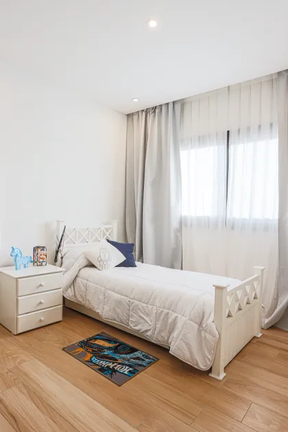 Dormitorio con cama blanca, cortinas blancas y suelo de madera clara — proyecto SS45, por EZ architects, en Pilar