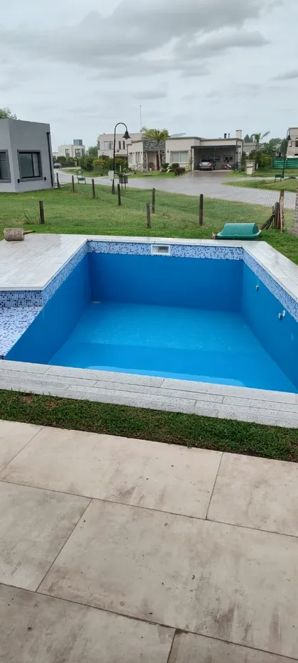 Pileta moderna con revestimiento azul en barrio residencial cerrado — proyecto Casa En El Barrio De Los Talas, por Ves Arquitectura , en Canning