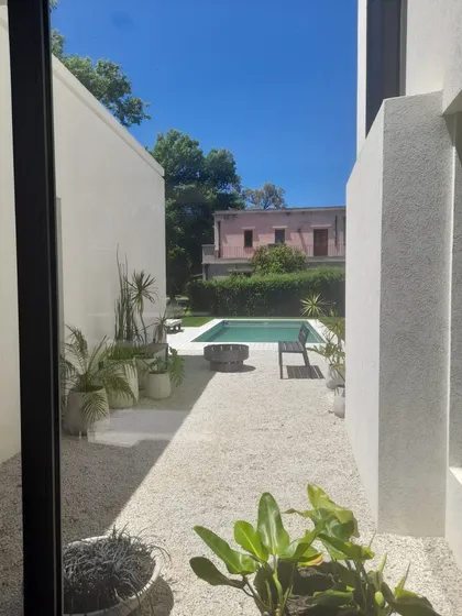 Patio moderno con pileta, jardín de grava y arquitectura blanca — proyecto El 54, por Valeria Damiani Arquitecta, en Pilar