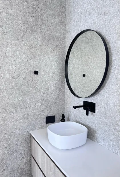 Baño moderno con revestimiento tipo terrazo, bacha redonda y grifería negra — proyecto DISEÑO INTERIOR - SAN BENITO - BAÑO SUITE , por FOCO_arquitectura&diseñointerior, en Belén de