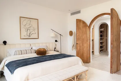 Dormitorio amplio con arco de madera y arte abstracto — proyecto El Refugio, por Grupo Pauta Arquitectura, en Pinamar