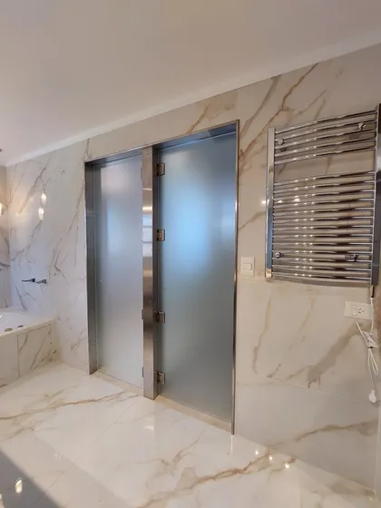 Baño moderno con ducha de cristal esmerilado y revestimiento de mármol — proyecto Reforma Interior - Village, por CM Espacio & Arquitectura, en Pilar