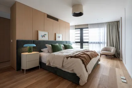 Dormitorio moderno con paredes de madera, cama azul y sillón blanco — proyecto Vidal, por Estudio Losa, en Belgrano