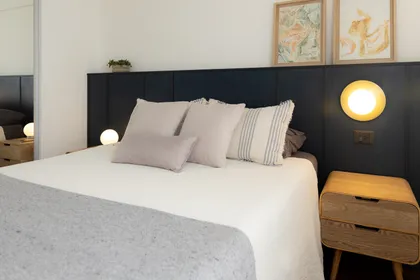 Dormitorio moderno con paneles de madera oscura y cama blanca — proyecto Arcos, por cromo., en Belgrano