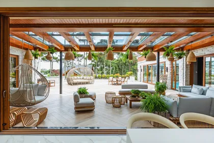 Terraza semiabierta con techo de pérgola de madera y muebles de rattan — proyecto Projeto Destaque Club&Casa, por OKA ARQUITETURA