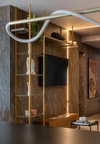 Living moderno con estantería dorada y luces indirectas — proyecto Argos Black - Living, por Geovani Capelina Arquitetura
