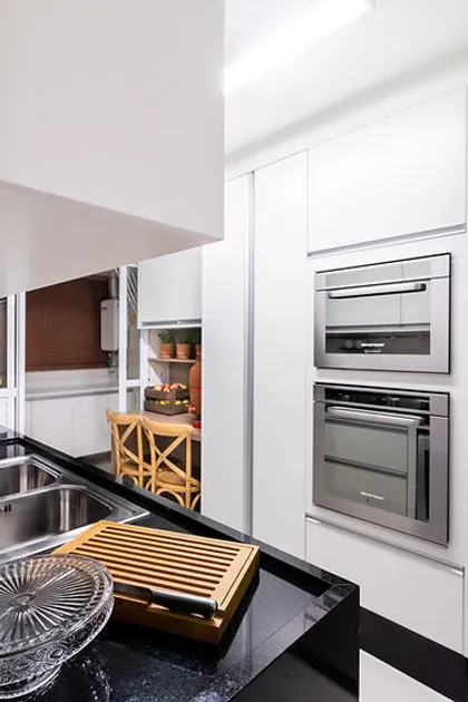 Cocina moderna blanca con mesada negra y electrodomésticos integrados — proyecto Apartamento Vila Leopoldina V, por Bordin E Soares Interiores
