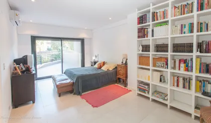 Dormitorio luminoso con cama azul, biblioteca blanca y balcón — proyecto San Isidro, por Rioja Arquitectura, en San Isidro