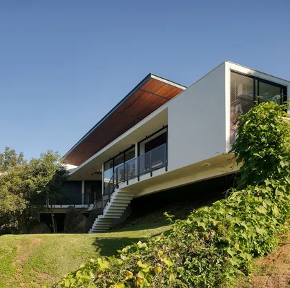 Casa contemporánea con fachada blanca, escalera externa y grandes ventanales — proyecto Casa das Pedras, por Tetro Arquitetura