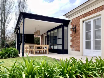 Galería exterior techada con pérgola de hierro negro y ventanales amplios — proyecto Martindale CC, por Marconi Silva Arquitectos, en Martindale Country Club