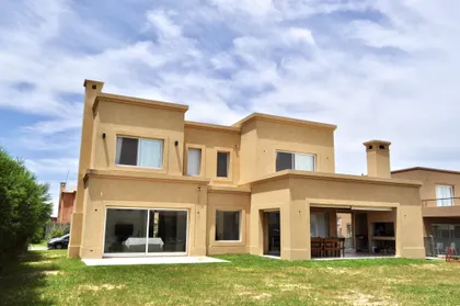 fachada trasera de casa moderna color arena con ventanales — proyecto Talar del Lago 3, por Marconi Silva Arquitectos, en General Pacheco