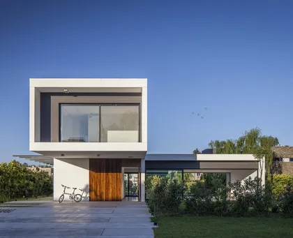 Moderna fachada blanca con volumen superior en voladizo y detalles en madera — proyecto CASA S2, por GMARQ