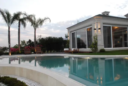Casa moderna con piscina y palmeras al atardecer — proyecto Sobriedad Francesa, por Oppel Arquitectura