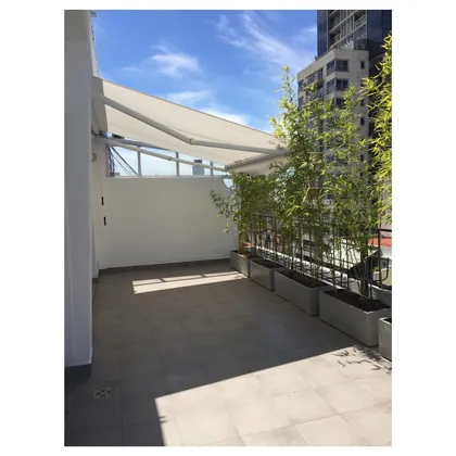 Terraza de balcón moderna con vegetación exuberante y toldo retráctil — proyecto GÜEMES, por Estudio ToyosQuesada, en Palermo