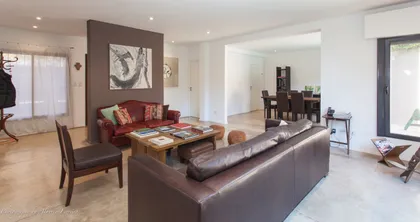 Living amplio con sofás, pared chocolate y conexión al comedor — proyecto San Isidro, por Rioja Arquitectura, en San Isidro
