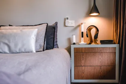 Dormitorio contemporaneo con cama gris, mesa de noche madera y lampara colgante negra — proyecto Cabrera, por Tali Estudio, en Palermo