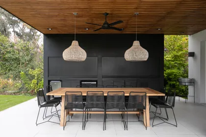 Comedor exterior moderno con techo de madera y luces tejidas — proyecto Obra Newman J, por Arq. Lourdes Yarade Saravia, en Benavidez