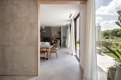 Living comedor moderno con pared de hormigón expuesto y grandes ventanales — proyecto Casa San Matías, por BK Arquitectos, en Belén de Escobar
