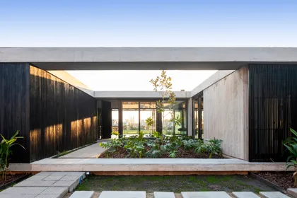 Fachada moderna con patio central y revestimiento de madera — proyecto Casa ROMA, por V2 Arquitectos, en City Bell